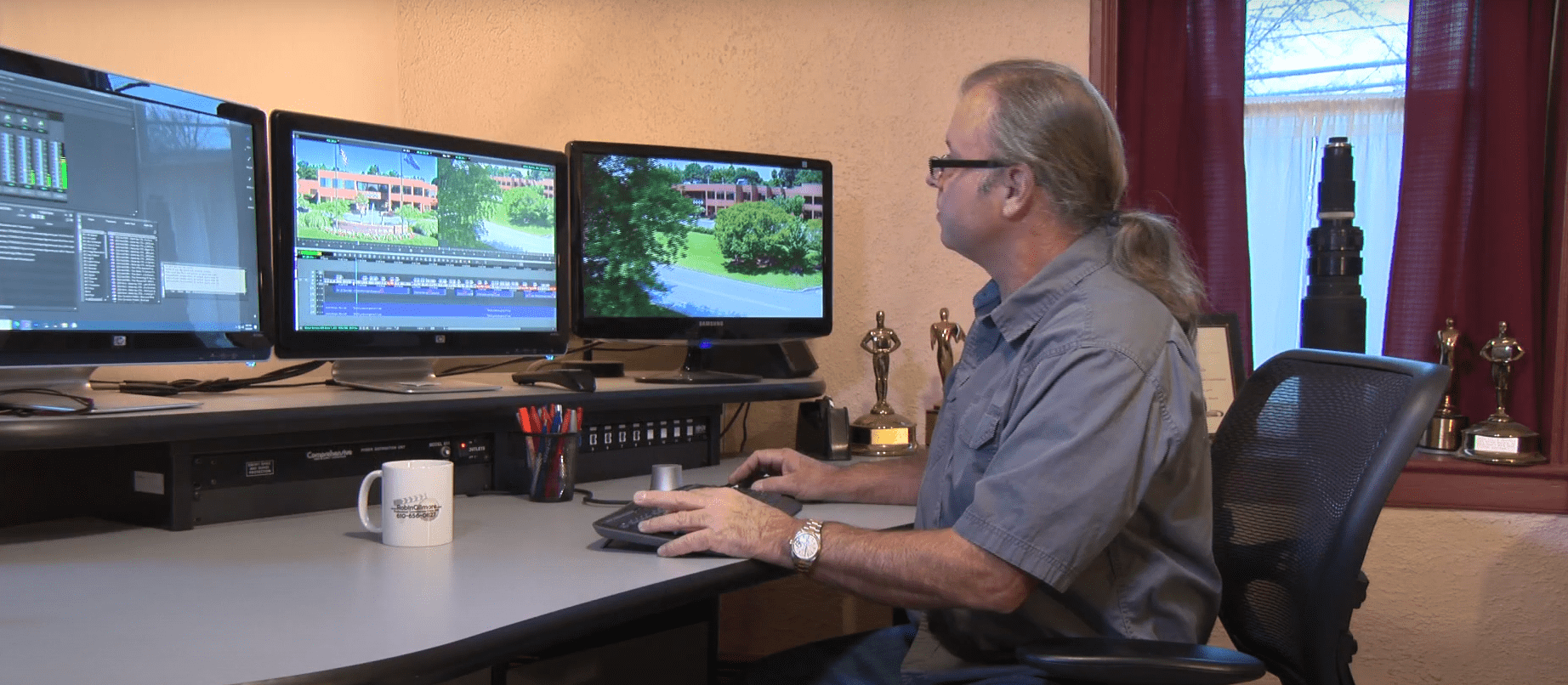 Picture of Robin at his workstation, surrounded by awards in the background from prior productions.
